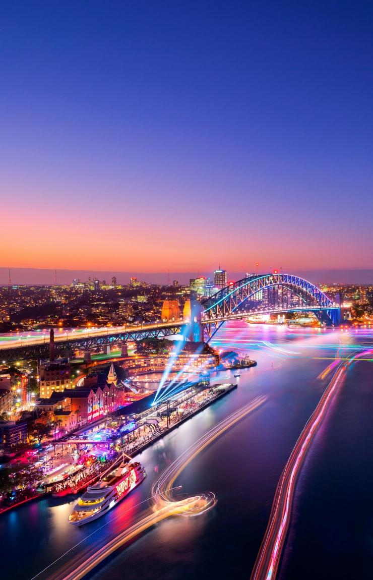 Luftaufnahme einer Hafenstadt geschmückt mit Regenbogenlichtern während Vivid Sydney, Sydney, New South Wales © Destination NSW