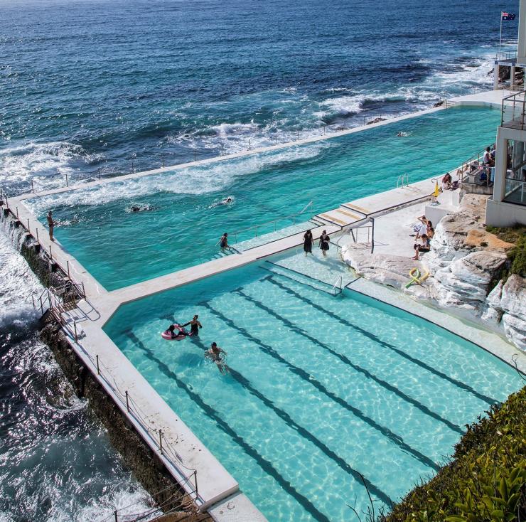 Luftaufnahme von Menschen, die im hellblauen Wasser von Bondi Icebergs am Bondi Beach schwimmen, Sydney, New South Wales © Destination NSW