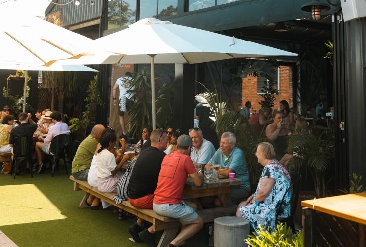 Groups of people seated at outdoor tables beneath umbrellas while drinking beer at One Drop Brewing, Botany, Sydney, New South Wales © One Drop Brewing Co Groups of people seated at outdoor tables beneath umbrellas while drinking beer at One Drop Brewing, Botany, Sydney, New South Wales © One Drop Brewing Co