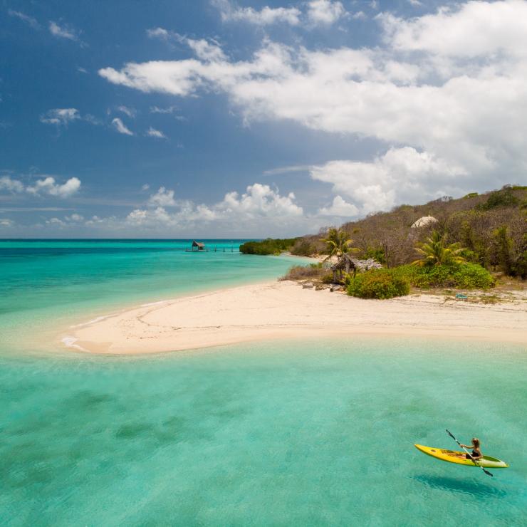 Person in kayak paddles in the ocean next to Haggerstone Island © Tourism and Events Queensland