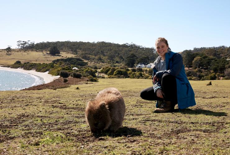 Hiker crouched next to a wombat along the Maria Island Walk  © Tourism Australia