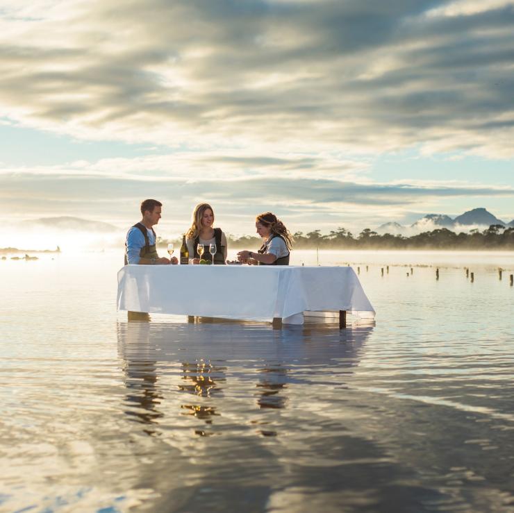 Three people stand in the water at a table tasting oysters at Saffire Freycinet Marine Oyster Farm in Tasmania’s Coles Bay © Saffire Freycinet/Tourism Tasmania Three people stand in the water at a table tasting oysters at Saffire Freycinet Marine Oyster Farm in Tasmania’s Coles Bay © Saffire Freycinet/Tourism Tasmania