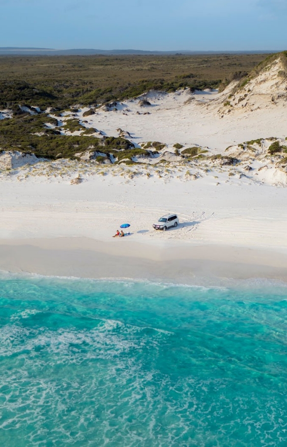 Couple sunbathing on the beach next to 4WD at Cape Le Grand National Park © Australia's Golden Outback