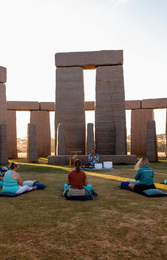 A group of women sitting in a circle on the grass, surrounded by large grey boulders in Esperance, Western Australia © Tourism Australia