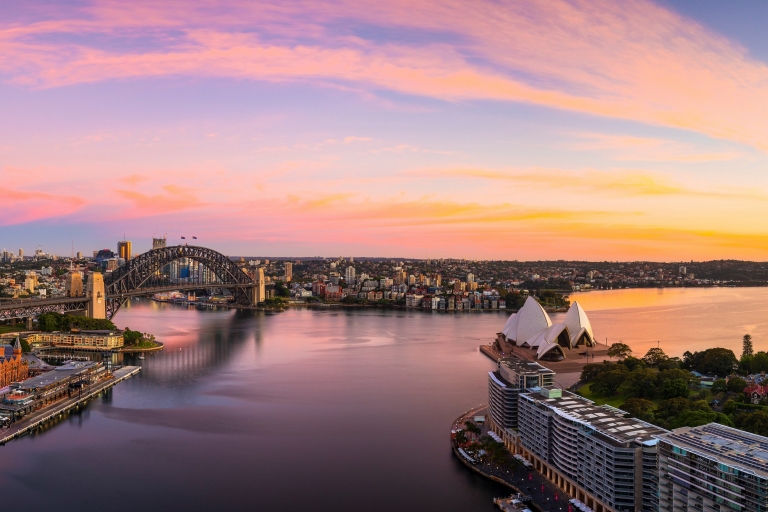 Aerial view of Sydney Harbour reflecting the blue, pink and gold hues of sunset in Sydney, New South Wales © Destination NSW