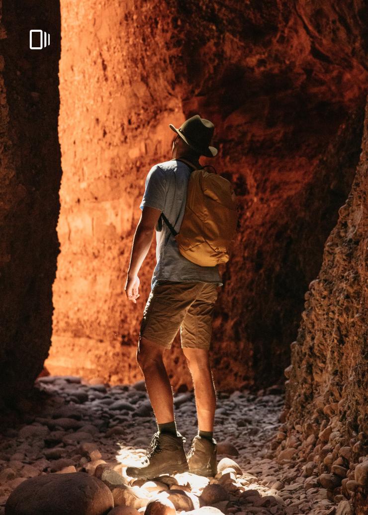 A man faces the red rock walls of Echidna Chasm in the Bungle Bungle Ranges, Western Australia © Tourism Australia