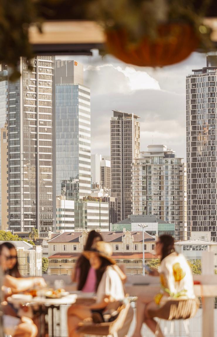 People sitting at tables on a rooftop bar overlooking a city skyline, Maya, Brisbane, Queensland © Brisbane Economic Development Agency