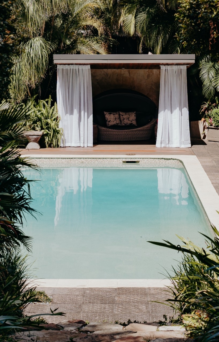 View through trees towards a pool and cabana surrounded by greenery at Gaia Retreat & Spa, Byron Bay, New South Wales © Gaia Retreat & Spa