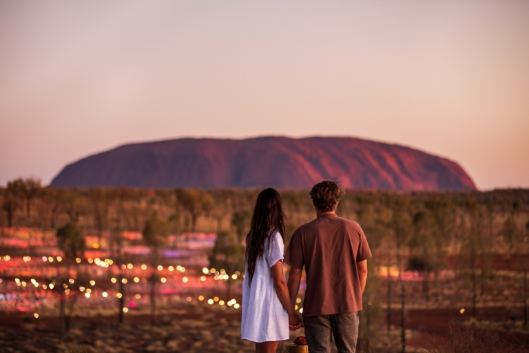 A couple standing in front of Uluru and the Field of Light during sunset in the Northern Territory © Tourism NT/The Salty Travellers A couple standing in front of Uluru and the Field of Light during sunset in the Northern Territory © Tourism NT/The Salty Travellers