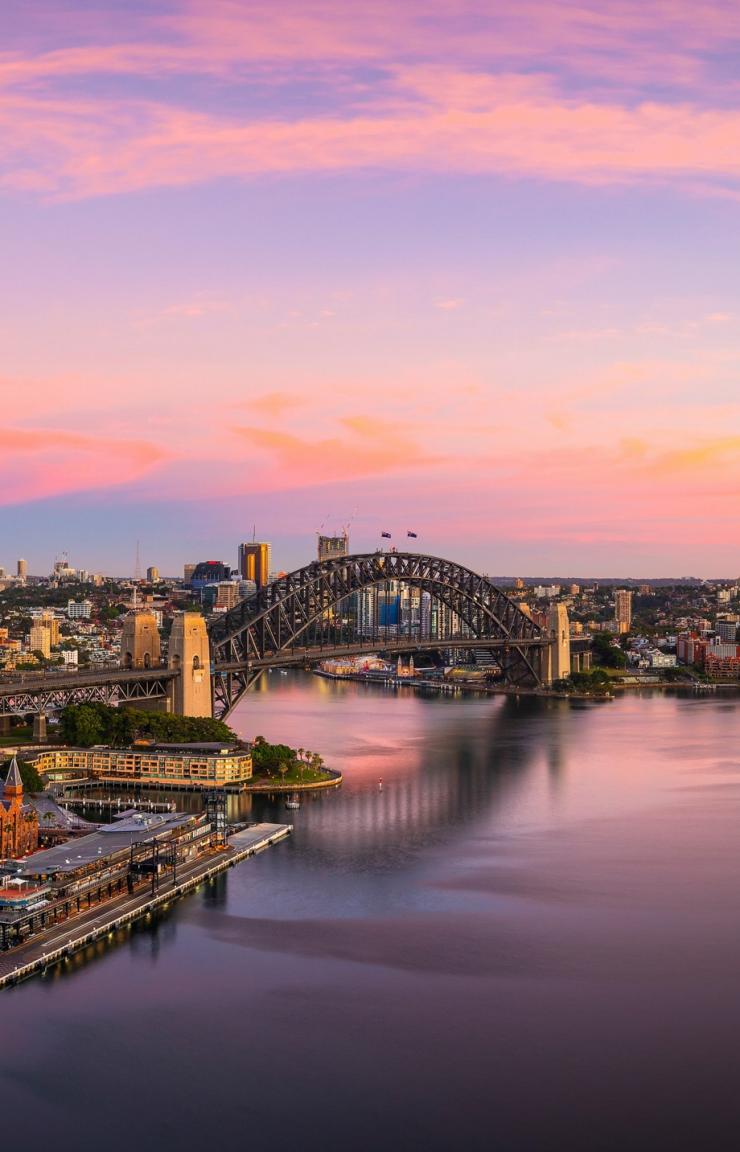 Aerial view of Sydney Harbour reflecting the blue, pink and gold hues of sunset in Sydney, New South Wales © Destination NSW Aerial view of Sydney Harbour reflecting the blue, pink and gold hues of sunset in Sydney, New South Wales © Destination NSW