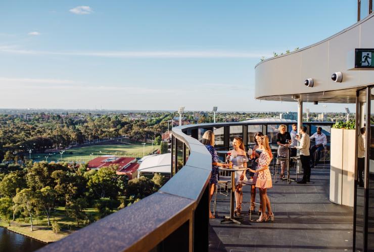 Un groupe d'amis réunis autour d'une table sirotant des boissons sur un rooftop qui surplombe la banlieue et le bush au SOL Rooftop, Adélaïde, Australie du Sud © Meaghan Coles Un groupe d'amis réunis autour d'une table sirotant des boissons sur un rooftop qui surplombe la banlieue et le bush au SOL Rooftop, Adélaïde, Australie du Sud © Meaghan Coles