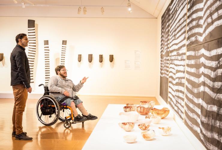 Homme en fauteuil roulant avec un autre homme debout contemplant une œuvre d'art au Araluen Arts Centre, Alice Springs, Territoire du Nord © Tourism NT/Helen Orr