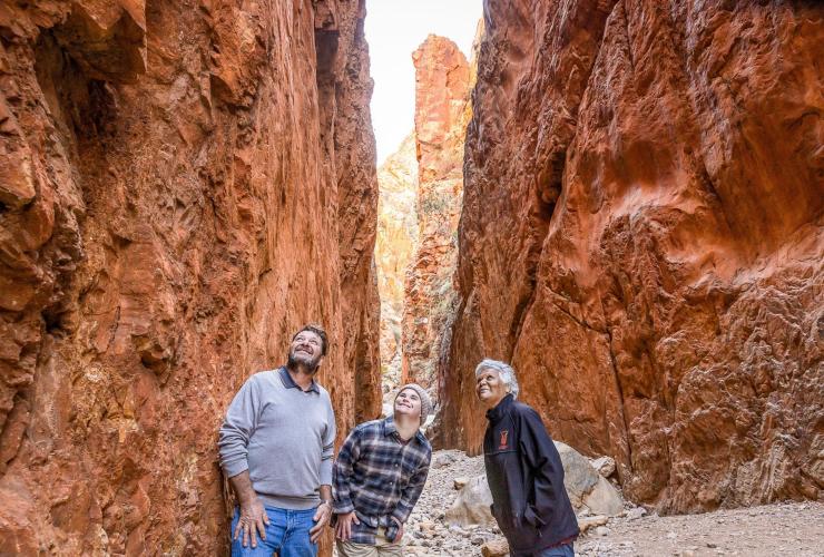 Homme neurodivergent explorant le Standley Chasm en compagnie d'un autre homme et d'un guide, West MacDonnell Ranges, Territoire du Nord © Tourism NT/Helen Orr