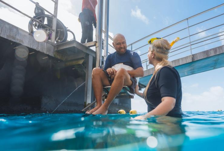 Utilisateur de fauteuil roulant descendant dans l'océan à l'aide d'un ascenseur aquatique avec Quicksilver Cruises, Grande Barrière de Corail, Queensland © Tourism and Events Queensland