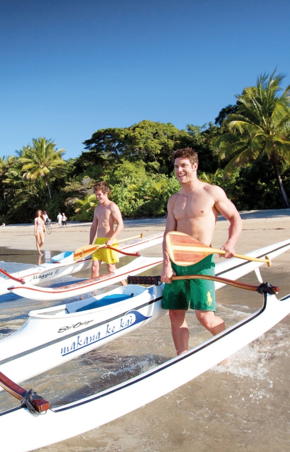 Des hommes poussant des bateaux dans l'océan à Four Mile Beach près de Port Douglas © Tourism Port Douglas and Daintree