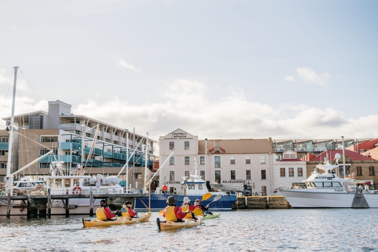 Groupe de personnes dans des kayaks jaunes évoluant dans une marina au milieu des bateaux avec Roaring 40s Kayaking à Hobart, Tasmanie © Tourism Australia