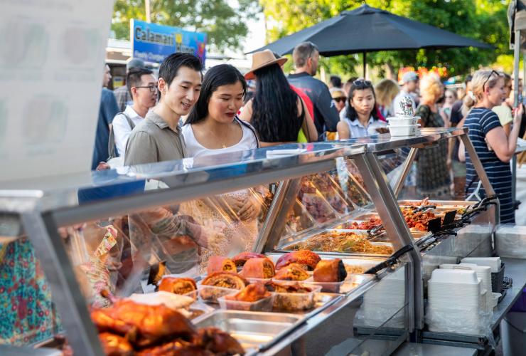 Pasangan melihat-lihat pilihan makanan di sebuah kios di Mindil Beach Sunset Market, Darwin, Northern Territory © Tourism NT/Helen Orr 