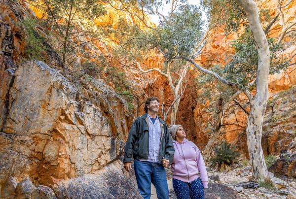 Seorang wanita dengan disabilitas saraf dan seorang pria menatap ke atas di Standley Chasm, West MacDonnell Ranges, Northern Territory © Tourism NT/Helen Orr