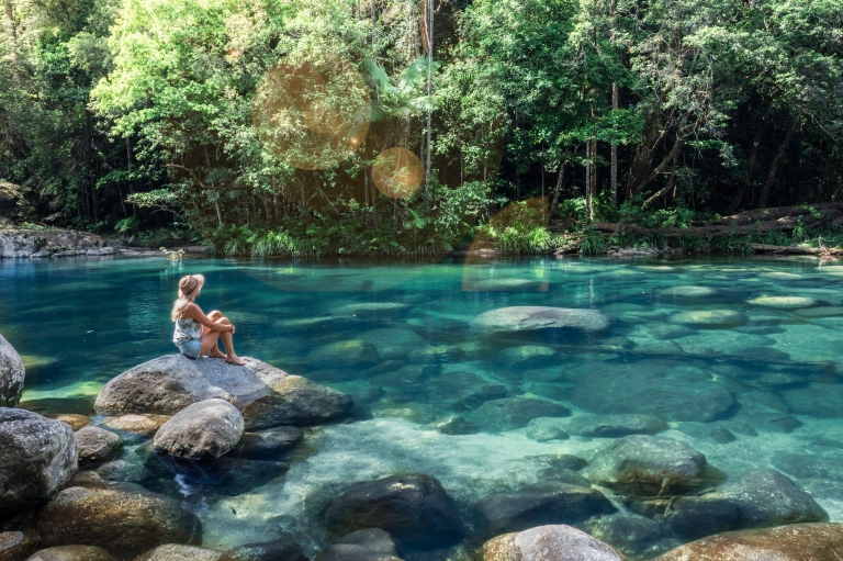 Wanita duduk di batu di dekat kolam bebatuan di Mossman Gorge © Tourism and Events Queensland