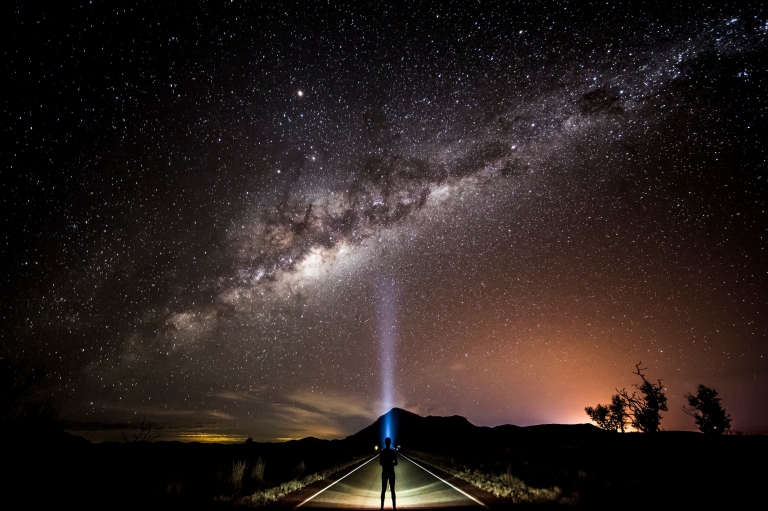 Visitatore intento ad ammirare le stelle della Via Lattea con una torcia © Tourism and Events Queensland/Sean Scott