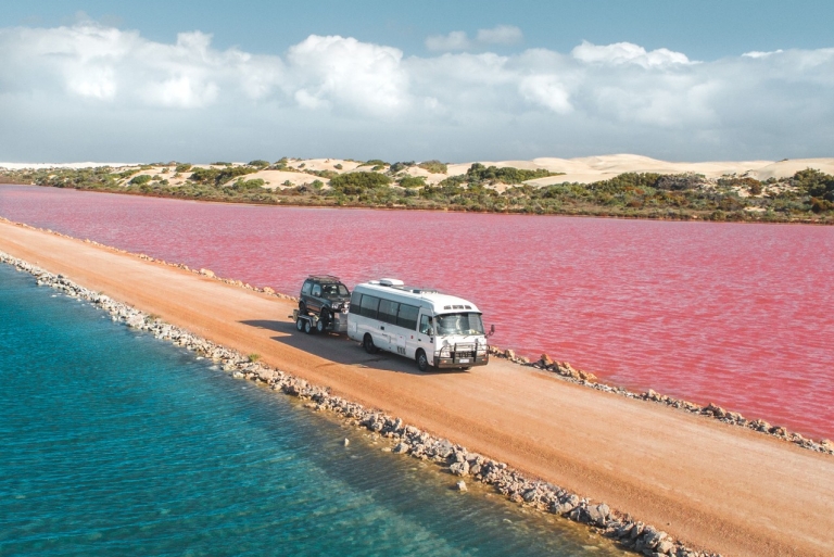 一輛客貨車在南澳州（South Australia）艾爾半島（Eyre Peninsula）麥克唐奈爾湖（Lake MacDonnell）的粉紅湖和綠湖（Green Lake）之間的泥路上行駛©Jaxon Foale