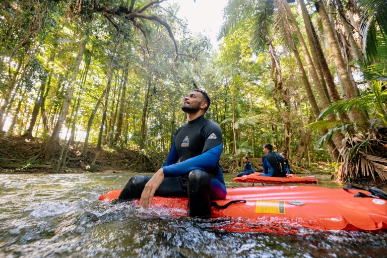 一名在昆士蘭州戴恩樹雨林參加Back Country Bliss Adventure活動的男士坐在河中的充氣船上仰望雨林的翠綠樹冠©澳洲旅遊局