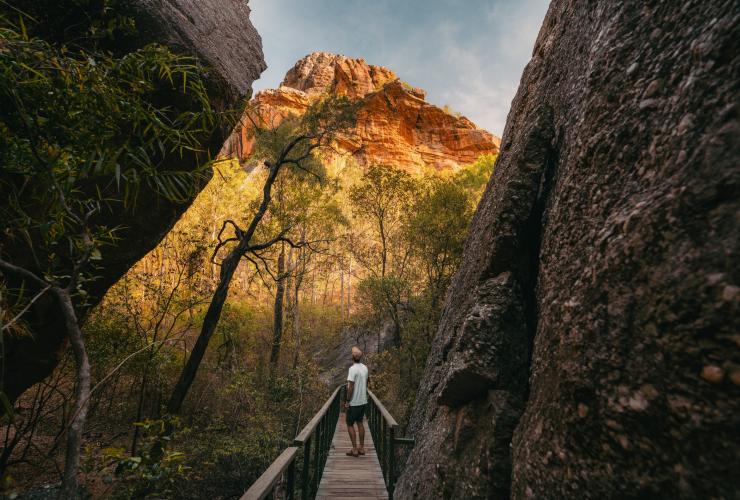 一名男子在北領地卡卡杜國家公園（Kakadu National Park）諾爾朗吉岩（Nourlangie Rock）旁步行©Hello Emily/北領地旅遊局