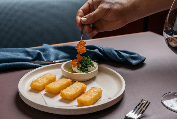 南澳阿德萊德Fugazzi Bar & Dining Room的菜式特寫鏡頭,有人正在一道擺盤精美的餐點上放上橙色魚籽©Julian Cebo 南澳阿德萊德Fugazzi Bar & Dining Room的菜式特寫鏡頭,有人正在一道擺盤精美的餐點上放上橙色魚籽©Julian Cebo