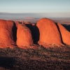 A large red rock monolith rising from the flat outback landscape at Uluru, Uluru-Kata Tjuta National Park, Northern Territory © Tourism Australia