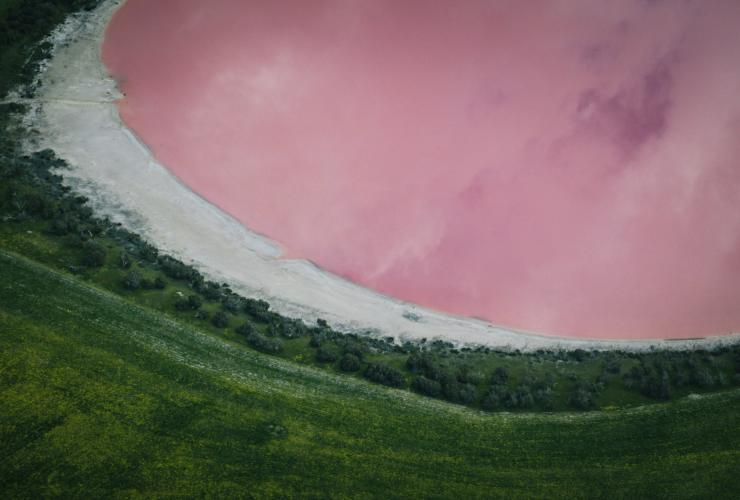 Aerial view over a pink lake surrounded by lush green grass at the Rainbow Lakes, Golden Outback, Western Australia © Golden Outback