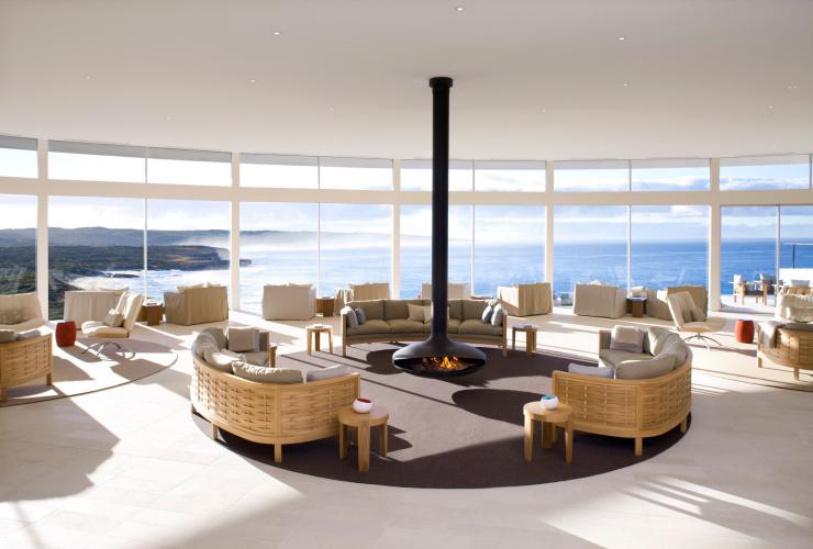 A large, light filled room overlooking the ocean fitted with lounges and chairs surrounding a fireplace at Southern Ocean Lodge, Kangaroo Island, South Australia © Southern Ocean Lodge