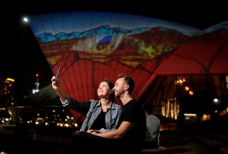 A couple taking a selfie in front of the Sydney Opera House at night, Sydney, New South Wales © Ken Leanfore
