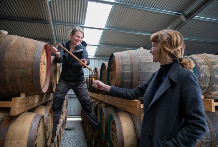 Staff member pouring a dark spirit from a barrel into a guest’s glass at Lark Distillery, Hobart, Tasmania © Tourism Australia