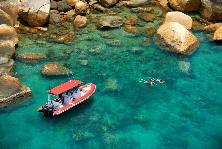 Aerial of a man and woman snorkelling among the fringing reef of Orpheus Island with a boat nearby at Orpheus Island Lodge, Queensland © Orpheus Island Lodge