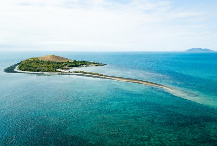 Aerial view over a lush green island surrounded by clear blue water at Camp Island Lodge, Whitsundays, Queensland © Camp Island Lodge