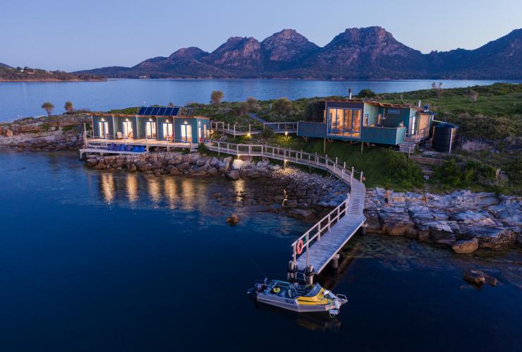 Two waterfront buildings and a pier jutting into the water with a boat at the end reflecting on the water during sunset on Picnic Island,  Coles Bay, Freycinet, Tasmania © Luke Tscharke