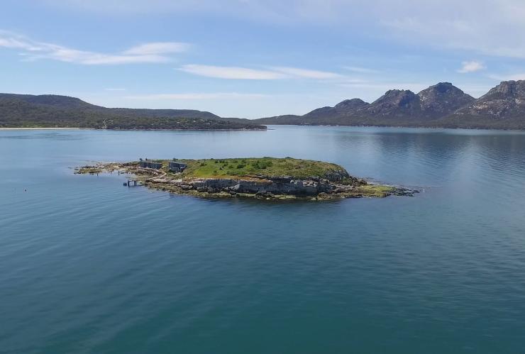 Aerial view over calm waters with the lush greenery of Picnic Island in the centre and a mountain range in the distance in Coles Bay, Freycinet, Tasmania © James Kerstan Photography