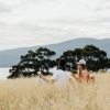 A couple picnicking on a grassy hill overlooking the ocean on Satellite Island, Tasmania © Adam Gibson