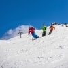 Two people with limited mobility adaptive skiing with instructors down a snow-covered mountain in Thredbo, Snowy Mountains, New South Wales © Tourism Australia
