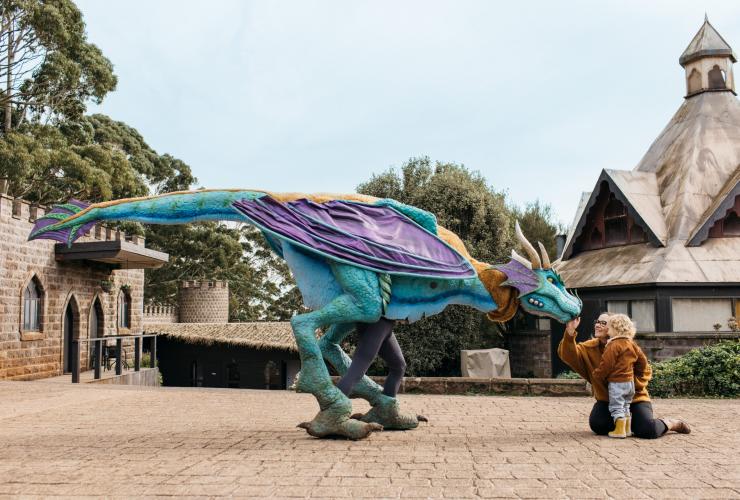 An actor dressed in an elaborate dragon costume greeting a mother and child at  Kryal Castle, Ballarat, Victoria © Tourism Australia/Visit Victoria