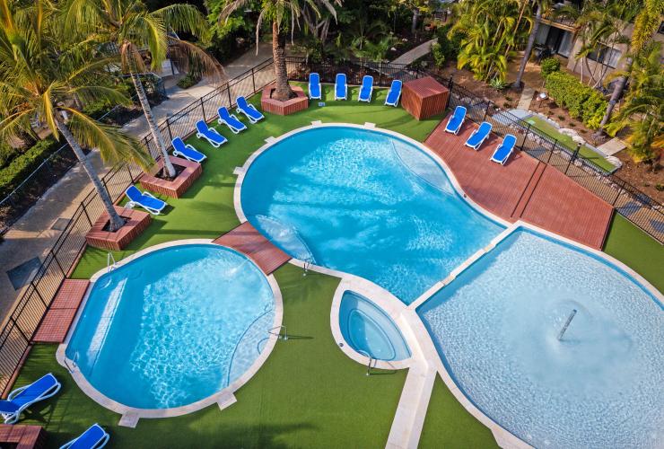 Aerial view over two blue pools surrounded by lounge chairs and trees at Turtle Beach Resort, Gold Coast, Queensland © Turtle Beach Resort