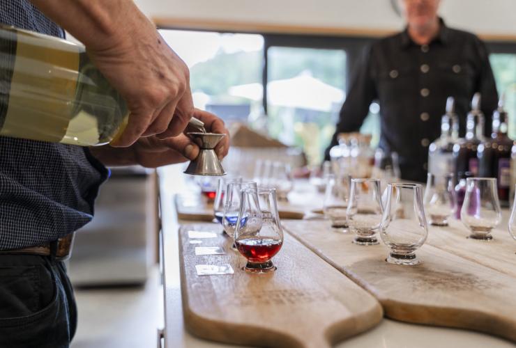 Closeup of bartender preparing tasting paddles of spirits at McHenry Distillery, Tasman Peninsula, Tasmania © Tourism Australia