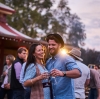 A historic pub with a wrap-around awning decorated with flags and a crowd of people gathered around outside sitting, drinking and talking at Birdsville Hotel, Birdsville, Queensland © Tourism and Events Queensland