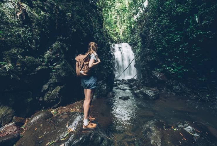 A girl standing with a backpack at the edge of Box Log Falls in Lamington National Park, Queensland © Tourism and Events Queensland