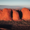 A large red rock monolith rising from the flat outback landscape at Uluru, Uluru-Kata Tjuta National Park, Northern Territory © Tourism Australia