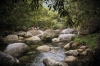 Wanita duduk di batu di dekat kolam bebatuan di Mossman Gorge © Tourism and Events Queensland