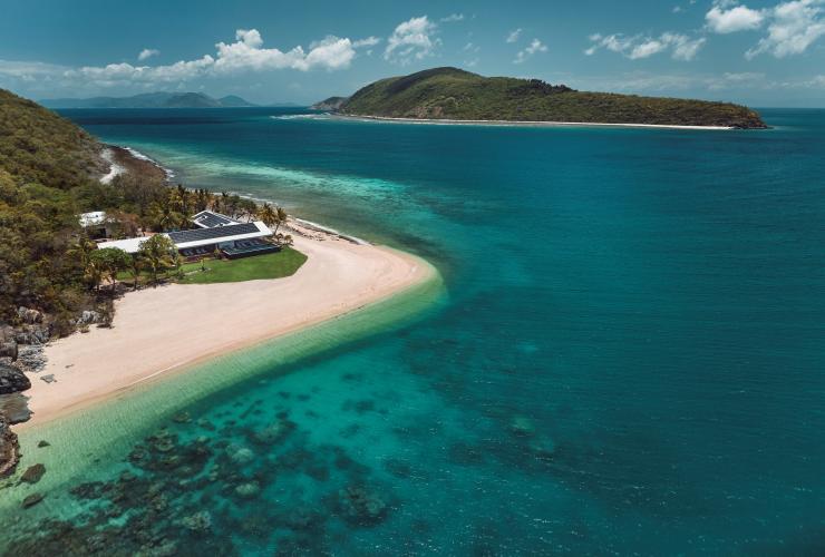 Vista aerea di un'isola con una spiaggia di sabbia bianca e acque cristalline e un'altra isola in lontananza a Pelorus Private Island, Palm Island, Queensland © Jason Ierace/Pelorus Private Island