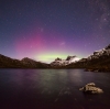 Aurora australe (luci del sud) che risplende con sfumature viola e verdi dietro alle vette innevate del Cradle Mountain-Lake St Clair National Park, Tasmania © Pierre Destribats