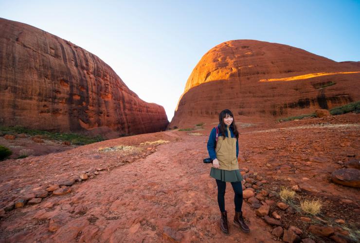 Persona in posa davanti a due maestose scogliere lungo il sentiero Valley of the Winds, Kata Tjuta, Red Centre, Northern Territory © Tourism NT/Salty Aura