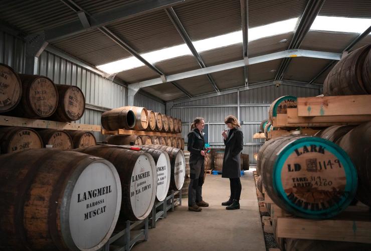 タスマニア州、ホバート、ラーク蒸留所の試飲体験にて、樽の列の間に立つ2人の女性 © Tourism Australia